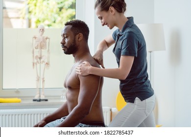 Physical Therapist Massaging A Young Black Man On Shoulder After A Sport Injury