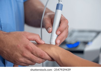 Physical therapist performs laser therapy on a patients wrist, targeting pain relief and promoting healing in a clinical setting - Powered by Shutterstock