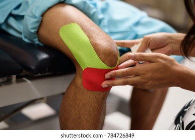 Physical therapist placing kinesio tape on patient's knee.Doctor hand taping for safety athlete muscle and joint.