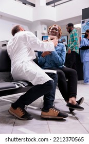 Physical Therapist Placing Neck Brace On Young African American Woman With Vertebral Injury At Hospital Emergency Medical Area. Specialist Checking Severity Of Patient Sprain.