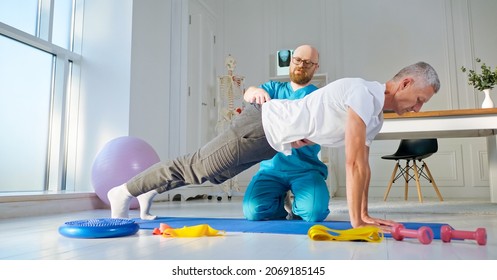 A Physical Therapist Safely Trains A Patient Using Medical Exercise Equipment At The Rehabilitation Center. Elderly Health Support Concept