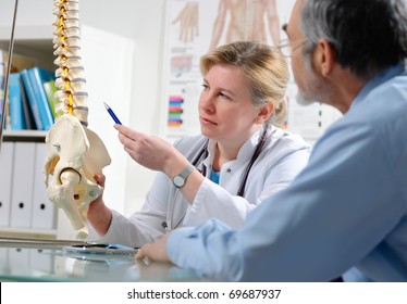 Physical Therapist Shows The Problem Areas On The Model Of The Spine To Patient And Explains The Cause Of His Pain.