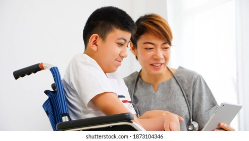 A Physical Therapist Is Talking To A Disabled Boy In A Wheelchair.