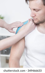 Physical Therapist Is Taping Young Man's Shoulder