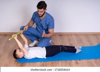 Physical Therapist Working With Little Girl In The Clinic, Exercising With The Stick