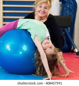 Physical Therapist Working With Little Girl In School Gymnasium, Exercising With Fitness Ball