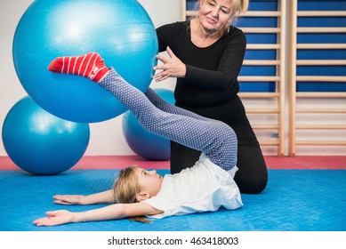 Physical Therapist Working With Little Girl In School Gymnasium, Exercising With Fitness Ball