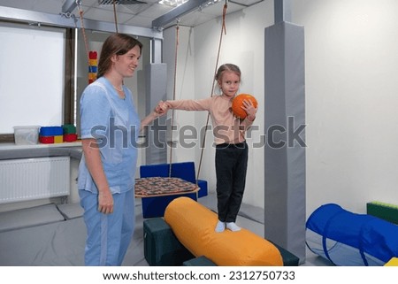 Physical therapist working with little girl in sensory room. Exercising for development of tactile sensations. Physiotherapy and neuro corrections in children therapy center