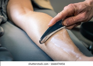 Physical therapy of a woman's calf being scraped for muscle recovery.