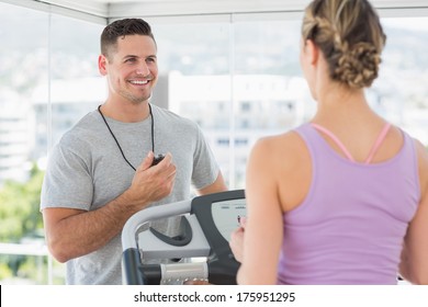 Physical Trainer Helping Woman On Treadmill At Gym