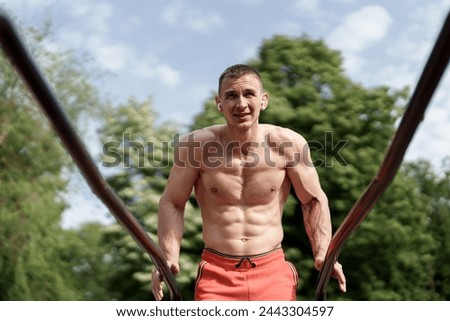 A physically fit man takes advantage of a beautiful sunny day to engage in an outdoor workout, showcasing strength and dedication in a natural setting.