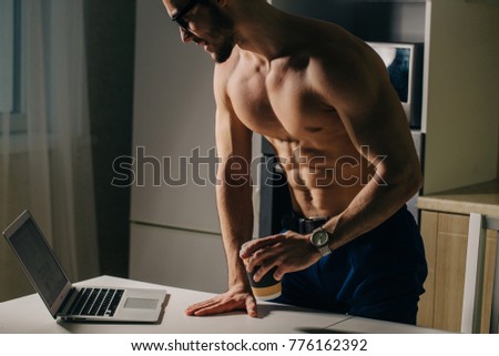 Physically Fit Man Using Laptop and drink coffee at morning