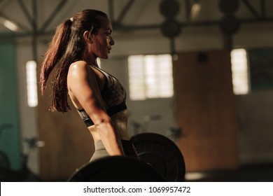 Physically fit woman lifting heavy weights. Fitness female doing heavy weight workout at gym.