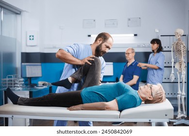 Physician assists retired woman with joint problems in obtaining orthopedic evaluation. Doctor does chiropractic exercises on elderly patient who has knee injury and is being treated for arthritis. - Powered by Shutterstock