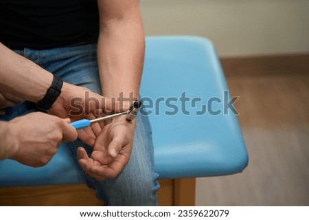Physician checking upper limb reflex in patient during neurological exam