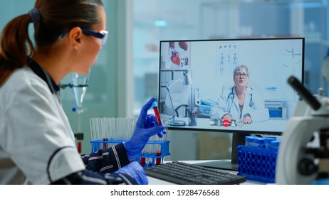 Physician doctor offering medical online advices to chemist student using pc. Scientist holding blood sample during online discussion, virtual conference, helping on telemedicine, healthcare support