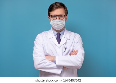 Physician Or Doctor Posing With A Face Mask On Isolated On Blue Background. Protection Against Flu Or Virus.