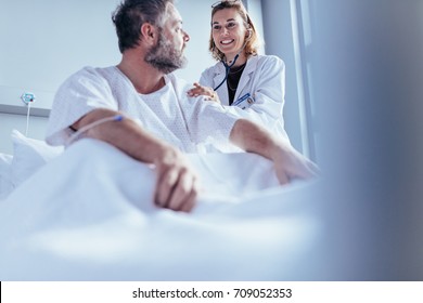 Physician Doing Routine Check Up Of Hospitalised Patient. Doctor Consoling A Patient In Ward At Hospital.