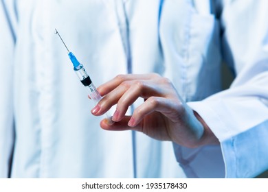 Physician hand with syringe for injection, vaccination. Vaccine or medicine against covid-19 in practitioner arm - Powered by Shutterstock