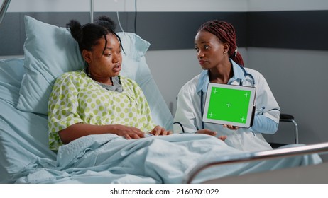 Physician Holding Digital Tablet With Horizontal Green Screen, Showing Technology To Patient. Medic And Person Looking At Isolated Mockup Template And Background On Chroma Key Display