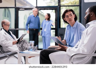 Physician medic explaining health care treatment to asian patient during checkup visit consultation in hospital office. Young man signing medical papers before start examination. Medicine service