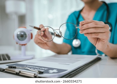 A physician performing an eye examination using an anatomical eye model and providing professional consultation and treatment in a medical setting to ensure proper diagnosis and vision care.