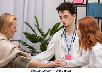 In A Physician's Office, A Nurse Practitioner Is Taking The Blood Pressure Of A Fifty-year-old Female Patient. A Primary Care Physician And An Intern