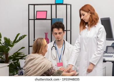 In A Physician's Office, A Nurse Practitioner Is Taking The Blood Pressure Of A Fifty-year-old Female Patient. A Primary Care Physician And An Intern