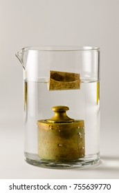 Physics. A cork floats in water and  a antique weight sinks. Archimedes Principle.