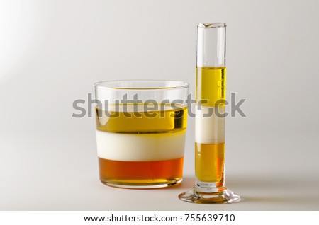 Physics. Density column. Laboratory glassware containing separed layers of vegetable oil, milk and honey.