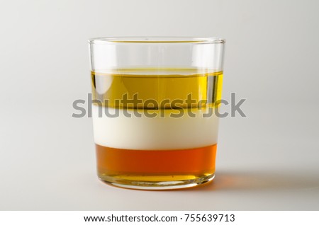 Physics. Density column. Laboratory glassware containing separed layers of vegetable oil, milk and honey.
