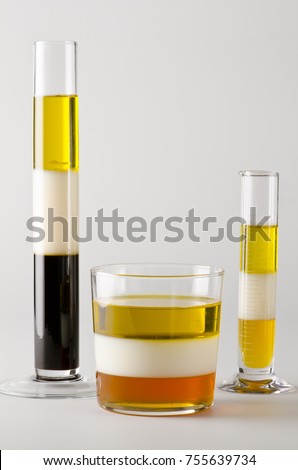 Physics. Density column. Laboratory glassware containing separed layers of vegetable oil, milk and maple syrup.
