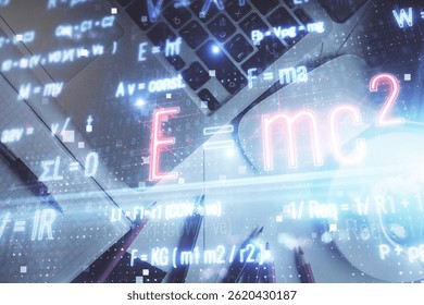 Physics and math theme hologram with formula drawings over computer on the desktop background. Top view. Multi exposure. Concept of education.