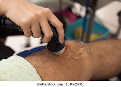 Physiologist using electro stimulation for treat knee pain.Doctor treatment for patient knee and leg muscles injuries, strains and tension in hospital physiotherapy medical rehabilitation clinic.