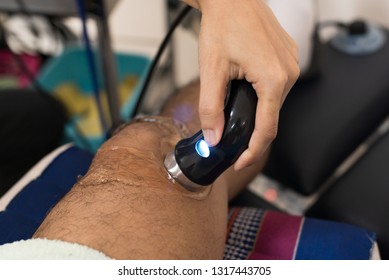 Physiologist using electro stimulation for treat knee pain.Doctor treatment for patient knee and leg muscles injuries, strains and tension in hospital physiotherapy medical rehabilitation clinic.