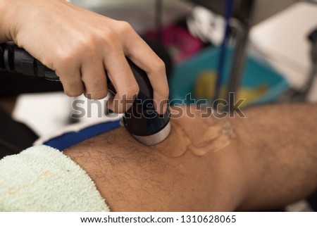 Physiologist using electro stimulation for treat knee pain.Doctor treatment for patient knee and leg muscles injuries, strains and tension in hospital physiotherapy medical rehabilitation clinic.
