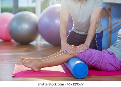 Physiotherapist assisting woman while exercising on exercise mat in clinic