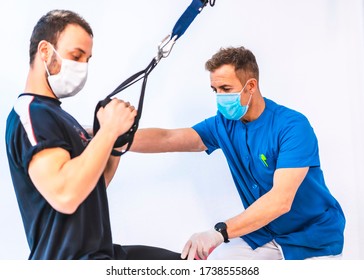 Physiotherapist in blue gown with a patient doing exercises with the arms. Physiotherapy with protective measures for the Coronavirus pandemic, COVID-19. Osteopathy, sports chiromassage - Powered by Shutterstock