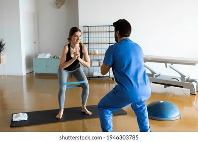 Physiotherapist in blue uniform demonstrating at female patient the position to exercise the legs and knees during rehabilitation session in loft studio or medical center, indoors. Wellness, recovery. - Powered by Shutterstock