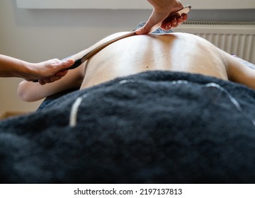 Physiotherapist correcting joint pain of male patient with IASTM tool, Instrument assisted soft tissue mobilization technique for soft tissue treatment. - Shutterstock ID 2197137813