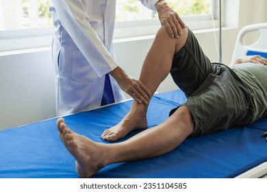 The physiotherapist doctor works to monitor the treatment of the patient's injured knees and legs, he uses the handle to the patient's knee to determine pain. Injury therapist - Powered by Shutterstock