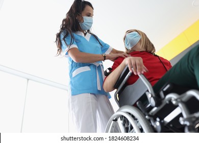 Physiotherapist Doing Back And Shoulder Massage To Disabled Young Woman In Wheelchair Wearing Protective Medical Masks. Rehabilitation Of People With Disabilities At Home In Context Of Covid19