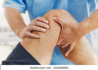 Physiotherapist doing healing treatment on patient leg. Therapist wearing blue uniform. Osteopathy, Chiropractic leg adjustment - Powered by Shutterstock