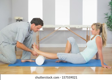 Physiotherapist examining patients foot while sitting on floor in bright room - Powered by Shutterstock