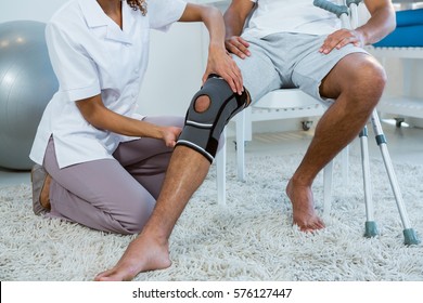 Physiotherapist examining patients knee in clinic