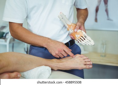 Physiotherapist explaining feet model to patient in clinic - Powered by Shutterstock