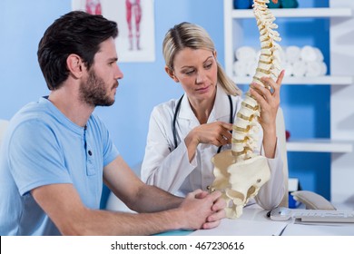 Physiotherapist explaining the spine model to patient in the clinic - Powered by Shutterstock