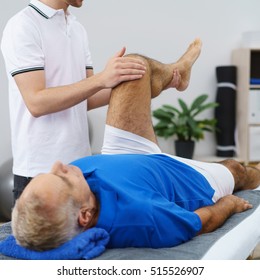 Physiotherapist flexing an elderly male patients knee as he performs an examination or mobility exercise