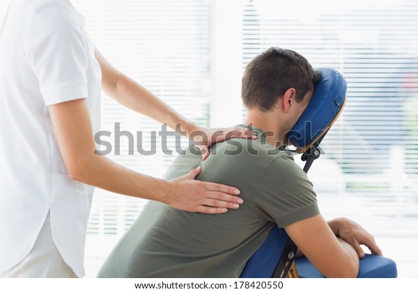Physiotherapist\
giving back massage to man in\
hospital