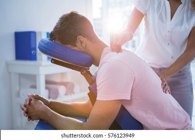 Physiotherapist giving back massage to a patient in clinic